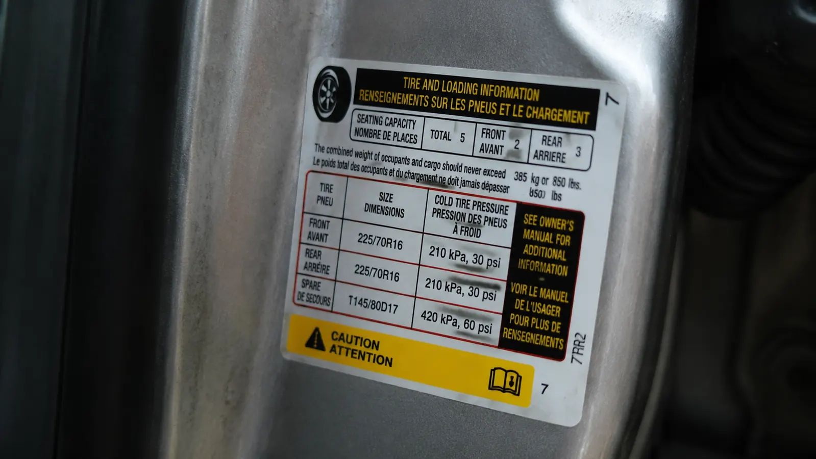Close-up of a tire pressure placard on a driver's side door jamb showing the recommended PSI
