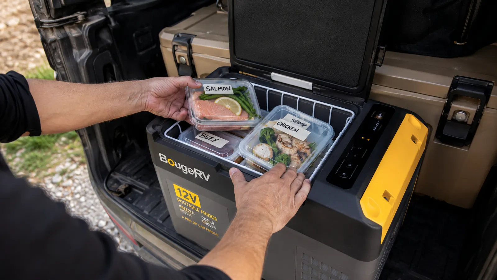 Hands placing a sealed container of food into an open portable 12V fridge in a vehicle cargo area, items organized by day